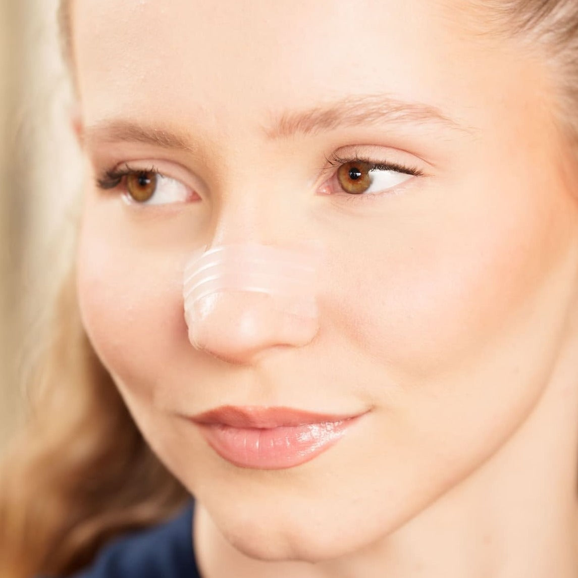 Tiras Nasales biOptimización - Variante Transparente - Mujer rubia con tira nasal aplicada en primer plano - Discreta, casi invisible y efectiva