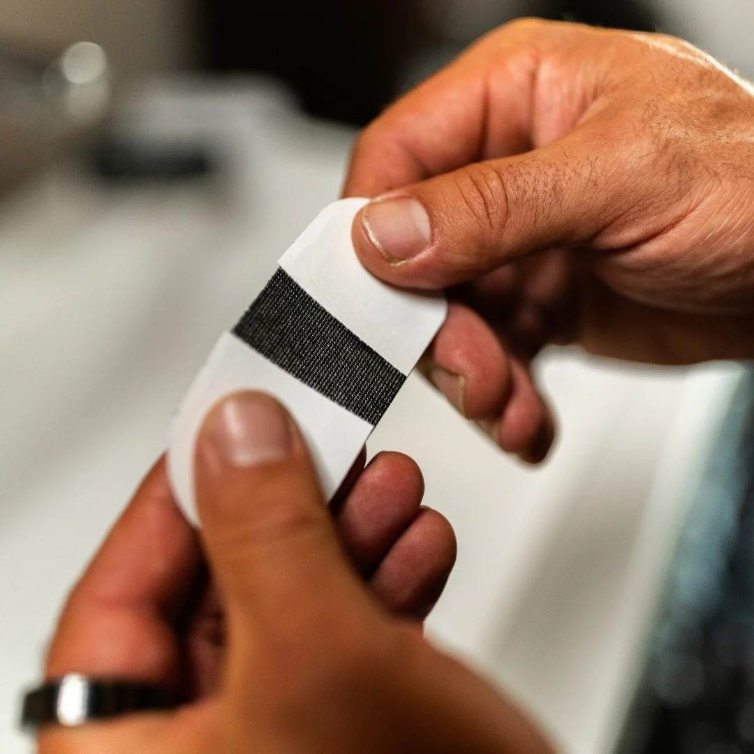 Cinta Bucal biOptimización - Manos retirando el protector de la cinta bucal negra - Cómo usar la cinta bucal paso a paso