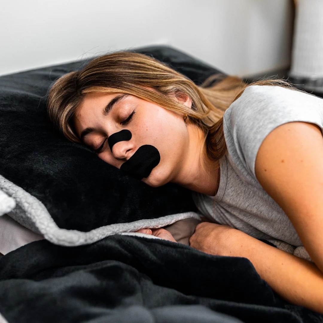 Cinta Bucal biOptimización - Mujer durmiendo profundamente con cinta bucal negra aplicada - Sueño reparador y descanso real toda la noche