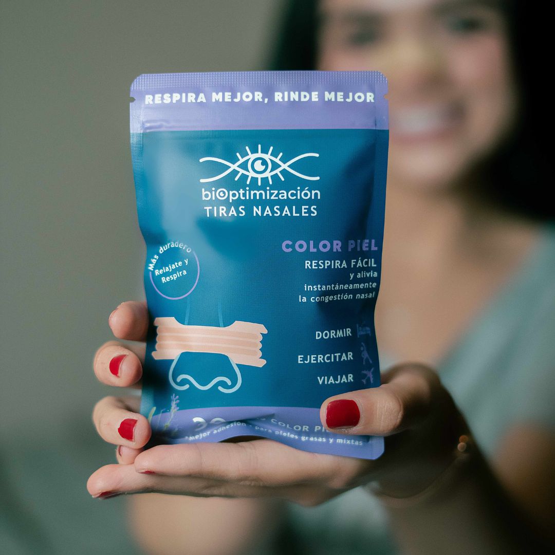 Tiras Nasales biOptimización - Variante Color Piel - Mujer sonriente sosteniendo el empaque del producto - Respira mejor, rinde mejor
