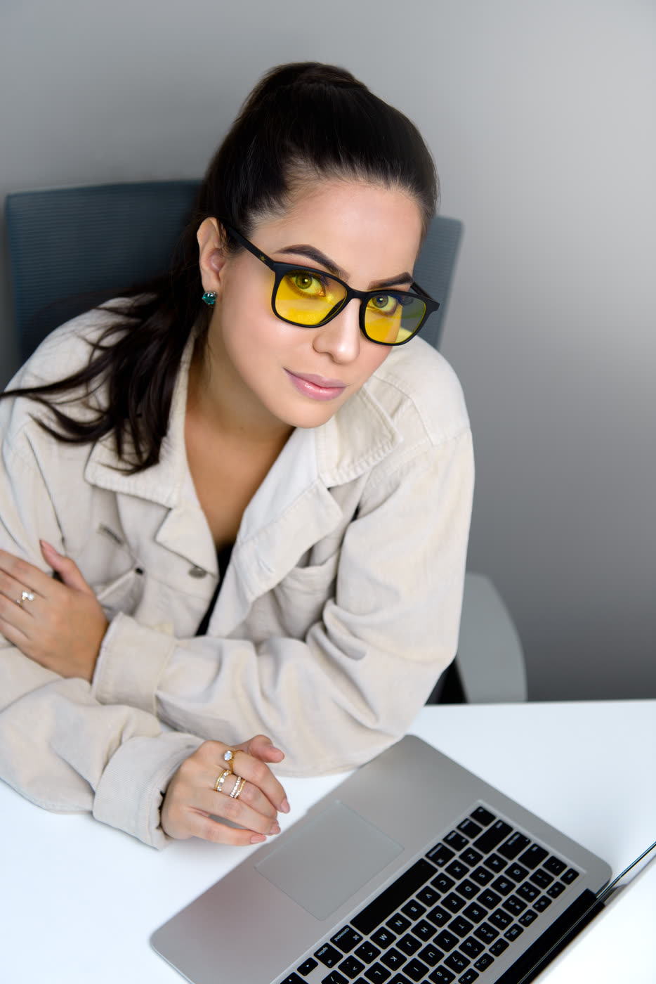 Mujer con los lentes Alpha Clarity puestos, sentada frente a su laptop mirando a cámara